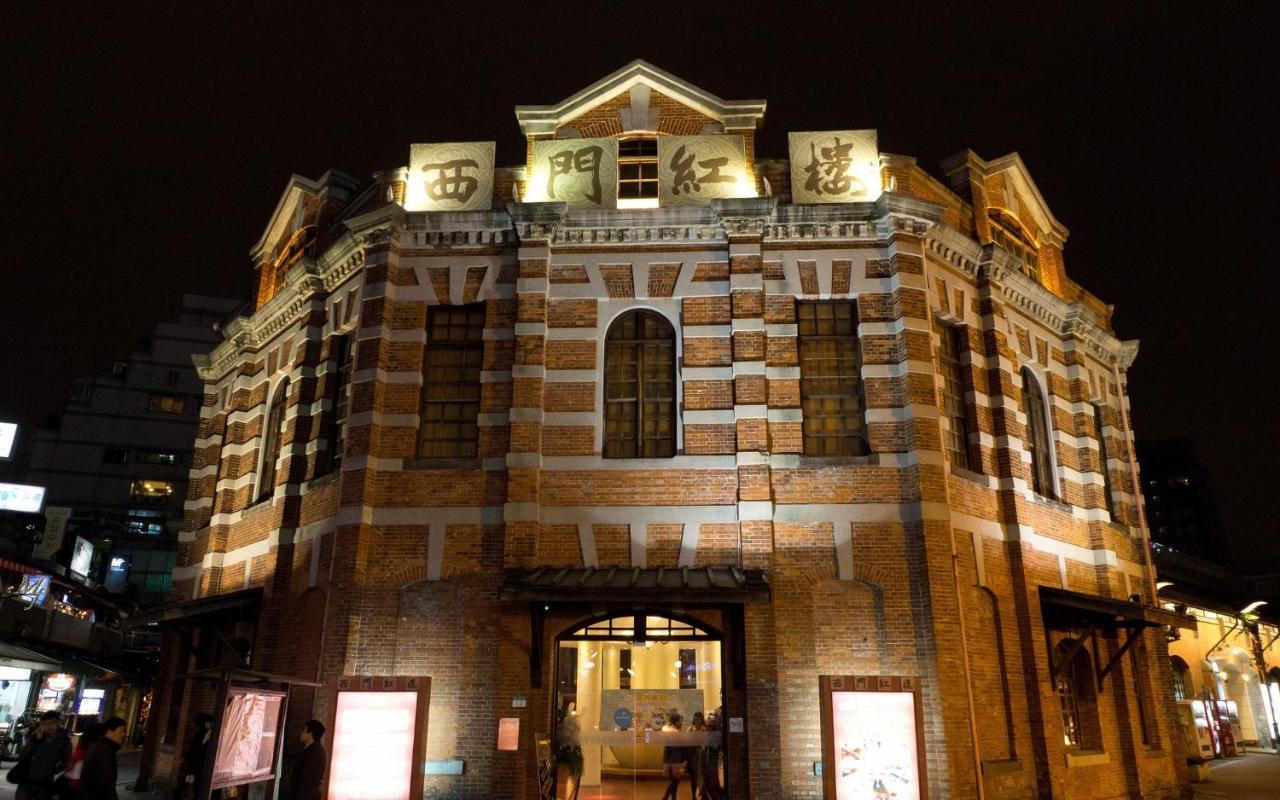 فندق سيزار مترو تايبيه المظهر الخارجي الصورة The photo shows a historical building illuminated at night. It features a distinct architectural style with a mix of brick and stone materials, characterized by a rounded structure and multiple windows. The front of the building is adorned with large