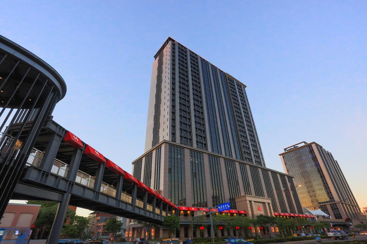 فندق سيزار مترو تايبيه المظهر الخارجي الصورة The photo depicts a modern high-rise building with a sleek design, featuring multiple floors and large windows. The structure is set against a clear sky, suggesting it is either early morning or late afternoon. In the foreground, there is a pedestria